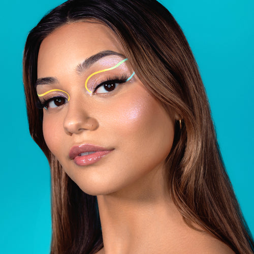 model wearing  the suva beauty hydra fx  color 'doodle daytrip' (yellow and blue) as a graphic eyeliner shown in daylight