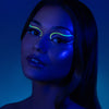 model wearing the suva beauty hydra fx  color 'doodle daytrip' (yellow and blue) as a graphic eyeliner shown in daylight