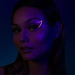 model wearing the suva beauty hydra fx color 'doodle delish' (purple and pink) as a graphic eyeliner shown in uv light